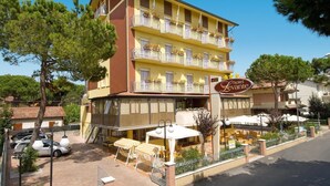 Un hotel de varios pisos con balcones, mobiliario exterior y cielo despejado.