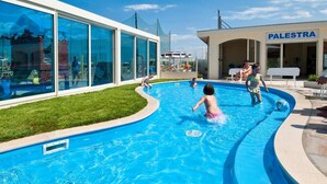A swimming pool area with a building labeled "PALESTRA" in the background. - Hotel Levante (Cervia)