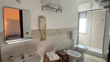 A bathroom with a sink, two basins, a mirror, a towel rack, and a shower area.