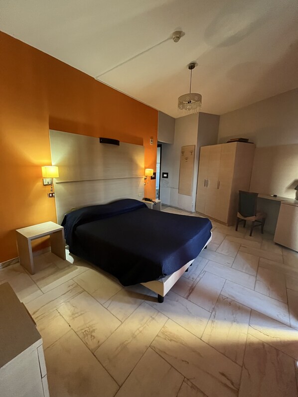 A modern bedroom with a bed, bedside lamps, a desk, and a wardrobe. - Hotel L'Approdo (Brindisi)