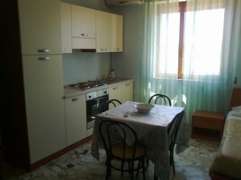Cocina compacta con estufa, horno y una mesa de comedor con sillas.