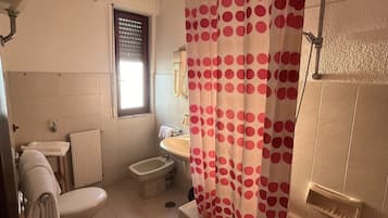 Un bagno con il water, bidet, lavandino e vasca da bagno.
