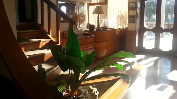 Een ruime woonruimte met een trap, een houten bureau, een lamp en een grote plant.