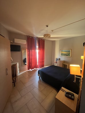 A hotel room with a bed, bedside table, lamp, air conditioning unit, and a painting on the wall. - Hotel L'Approdo (Brindisi)
