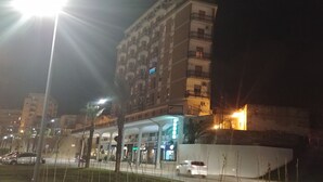 Een meerlaags gebouw met balkons, een overdekte doorgang en verlichte signage.