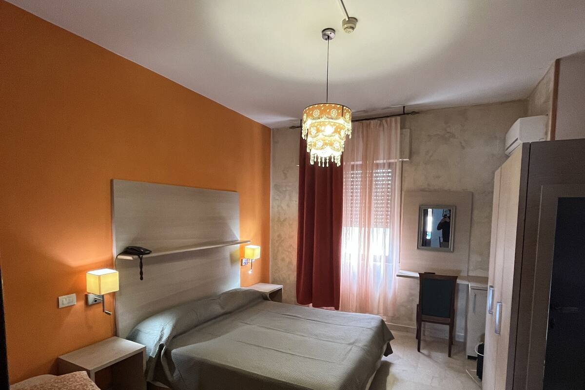 A hotel room with a large bed, bedside lamps, a television, and a desk.