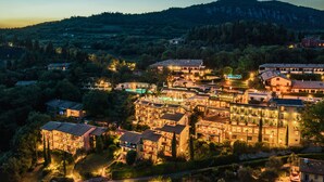 A hotel with multiple buildings, a pool area, and a mountainous backdrop. - Residence Madrigale (Costermano sul Garda)