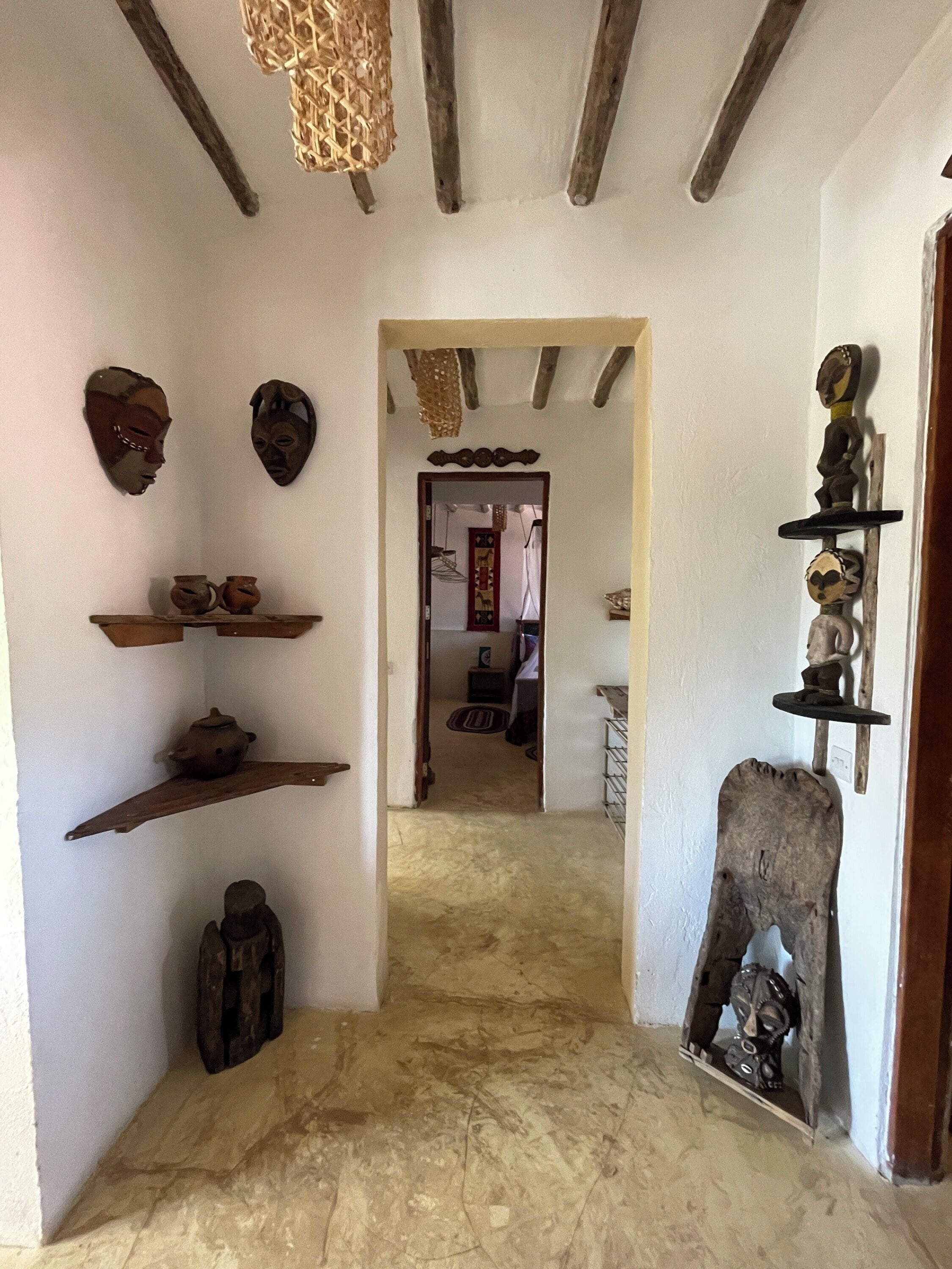 Un pasillo con vigas de madera, estantes con cerámica y decoración rústica.