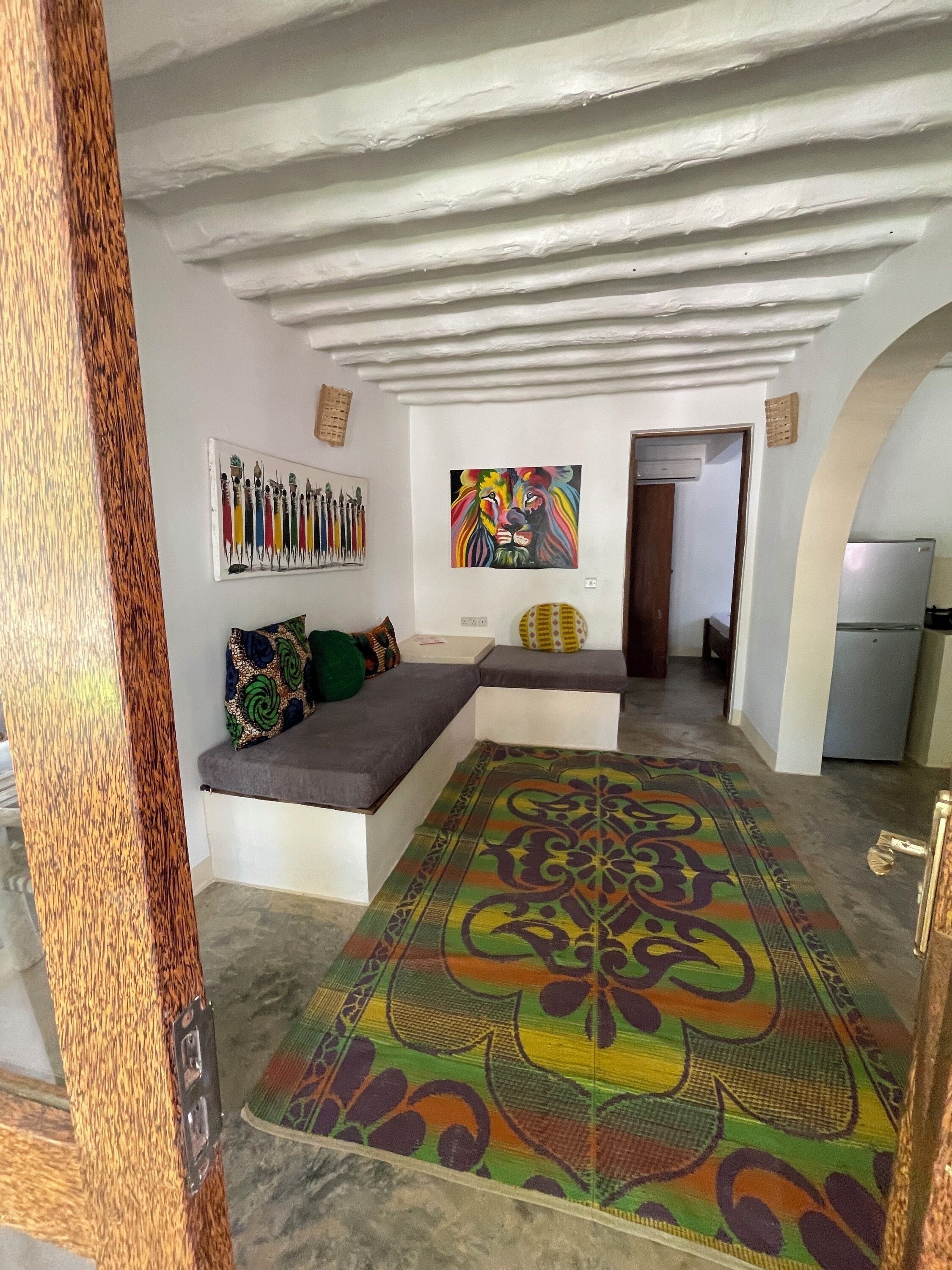 Un salon moderne avec un canapé d’angle, un tapis coloré et un tableau représentant des lions accroché au mur.
