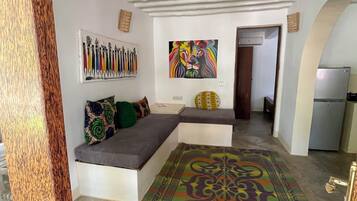Un salon moderne avec un canapé d’angle, un tapis coloré et un tableau représentant des lions accroché au mur.