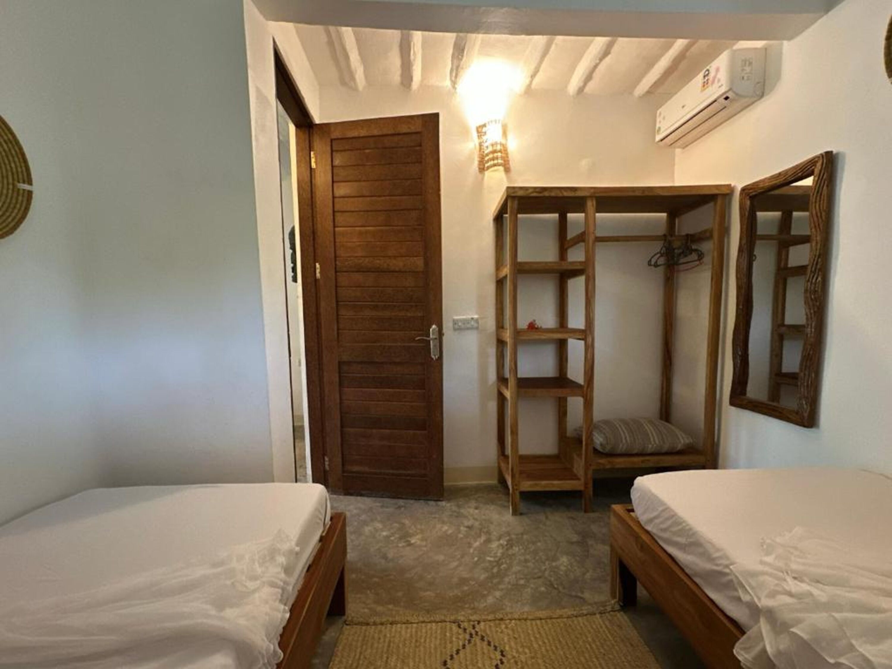 A room with two wooden beds, a wardrobe, and a mirror.