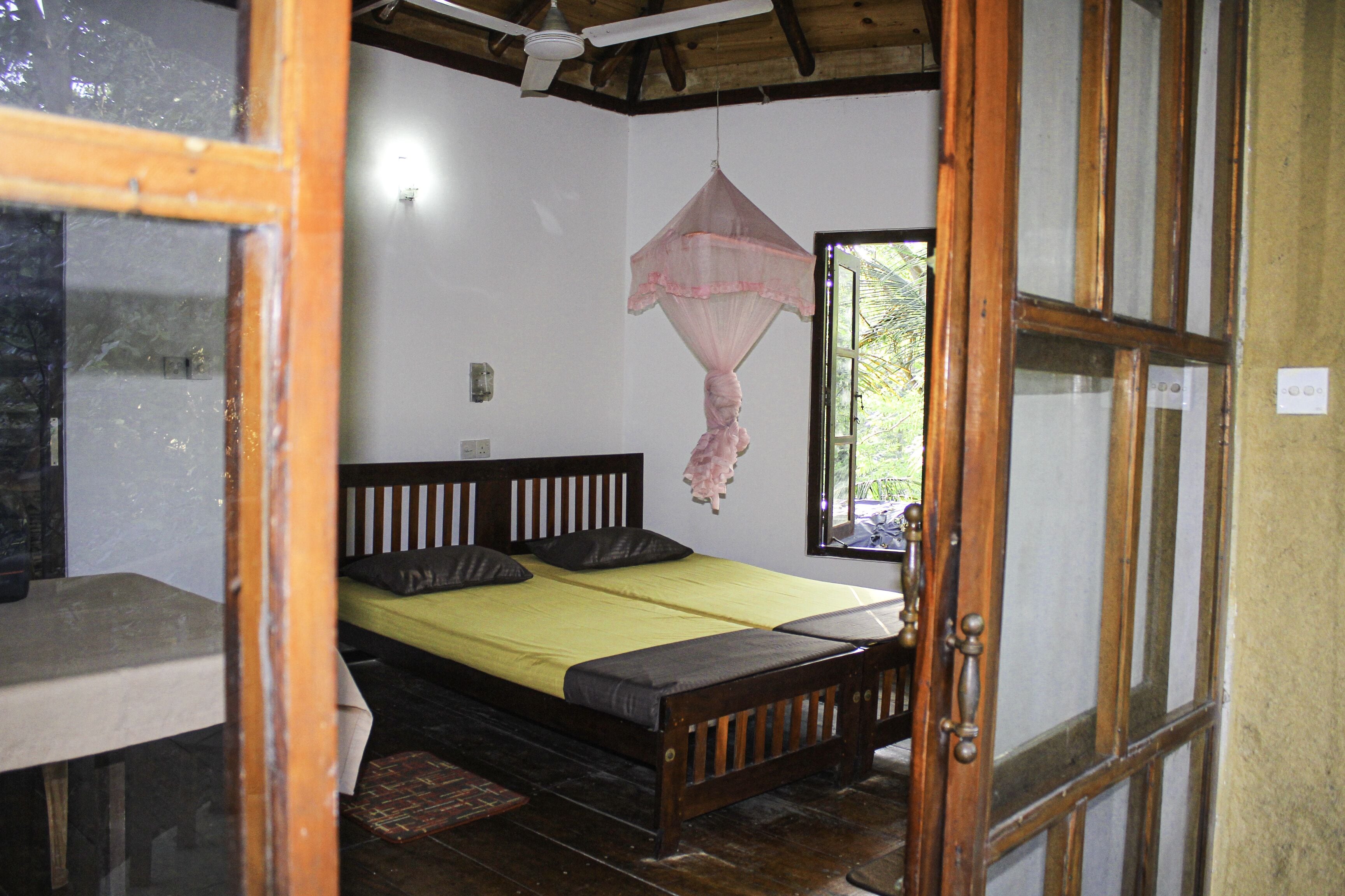 Una habitación con cama, ventana y mosquitera.