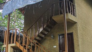 Un edificio de dos plantas con una escalera de madera y un balcón.