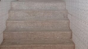 Una escalera con barandilla a la izquierda y un muro de azulejos a la derecha.