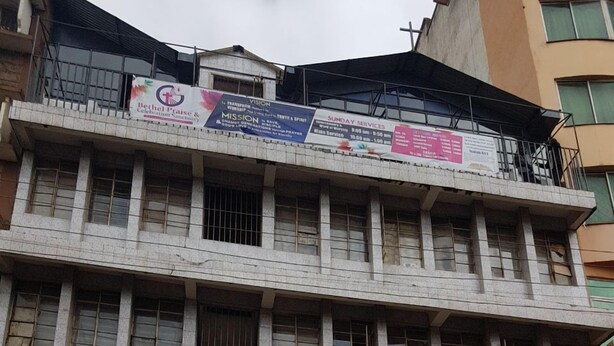 Un edificio de varios pisos con un cartel anunciando servicios dominicales.
