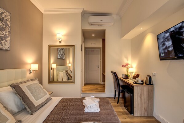Une chambre d’hôtel avec un lit, un bureau, une chaise, une télévision et un miroir.