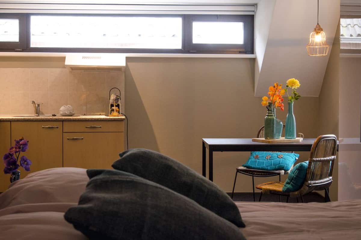 A bedroom with a bed, a nightstand, a dresser, and a window with curtains.