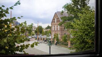 A traditional brick building with a prominent triangular roof, surrounded by trees and parked cars.