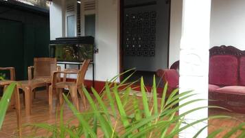 Una habitación con piso de madera, una mesa de comedor con sillas, un acuario, un sofá rojo y un biombo decorativo.