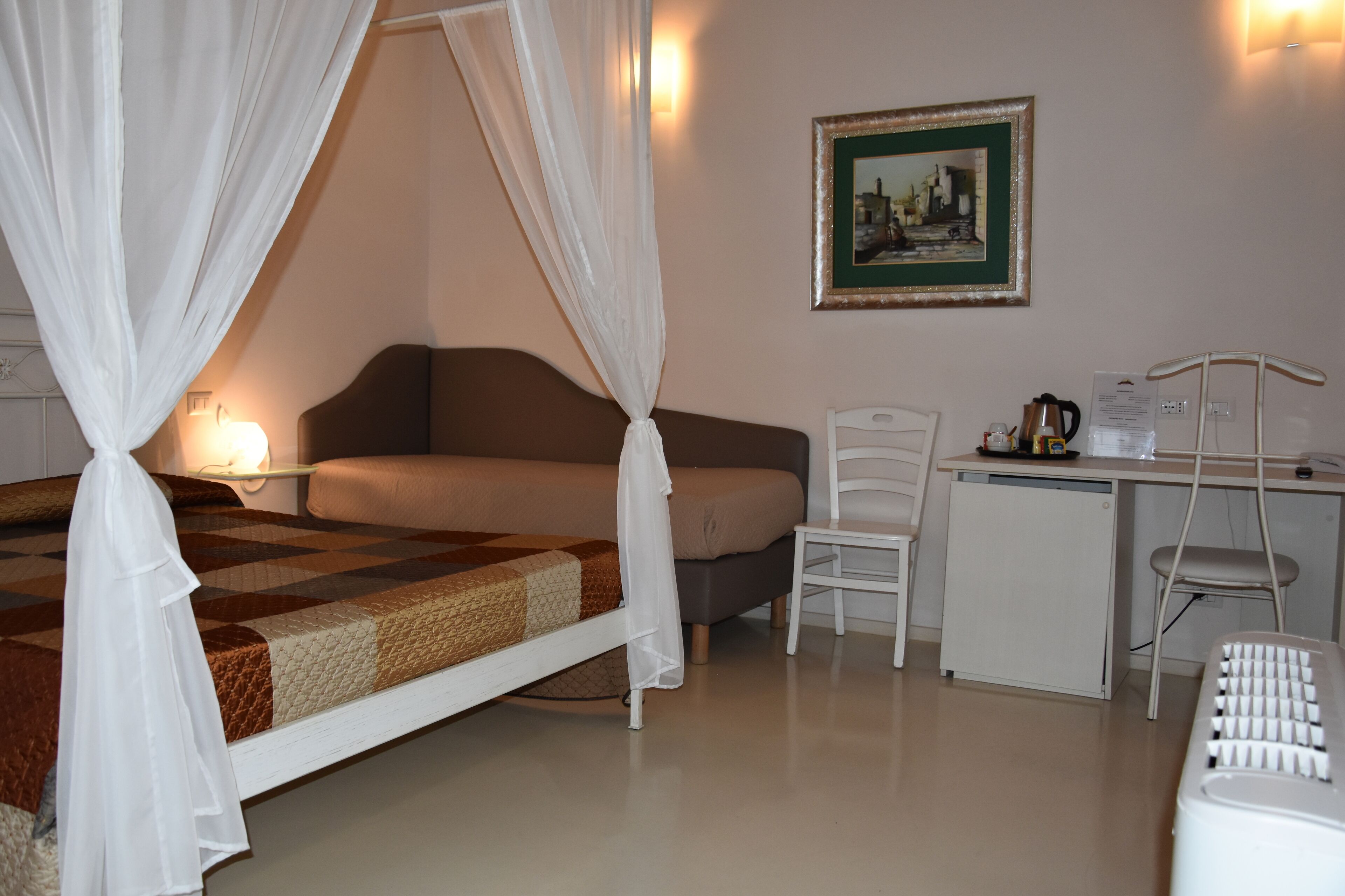 A bedroom with a bed, a desk, a chair, and a bedside table.
