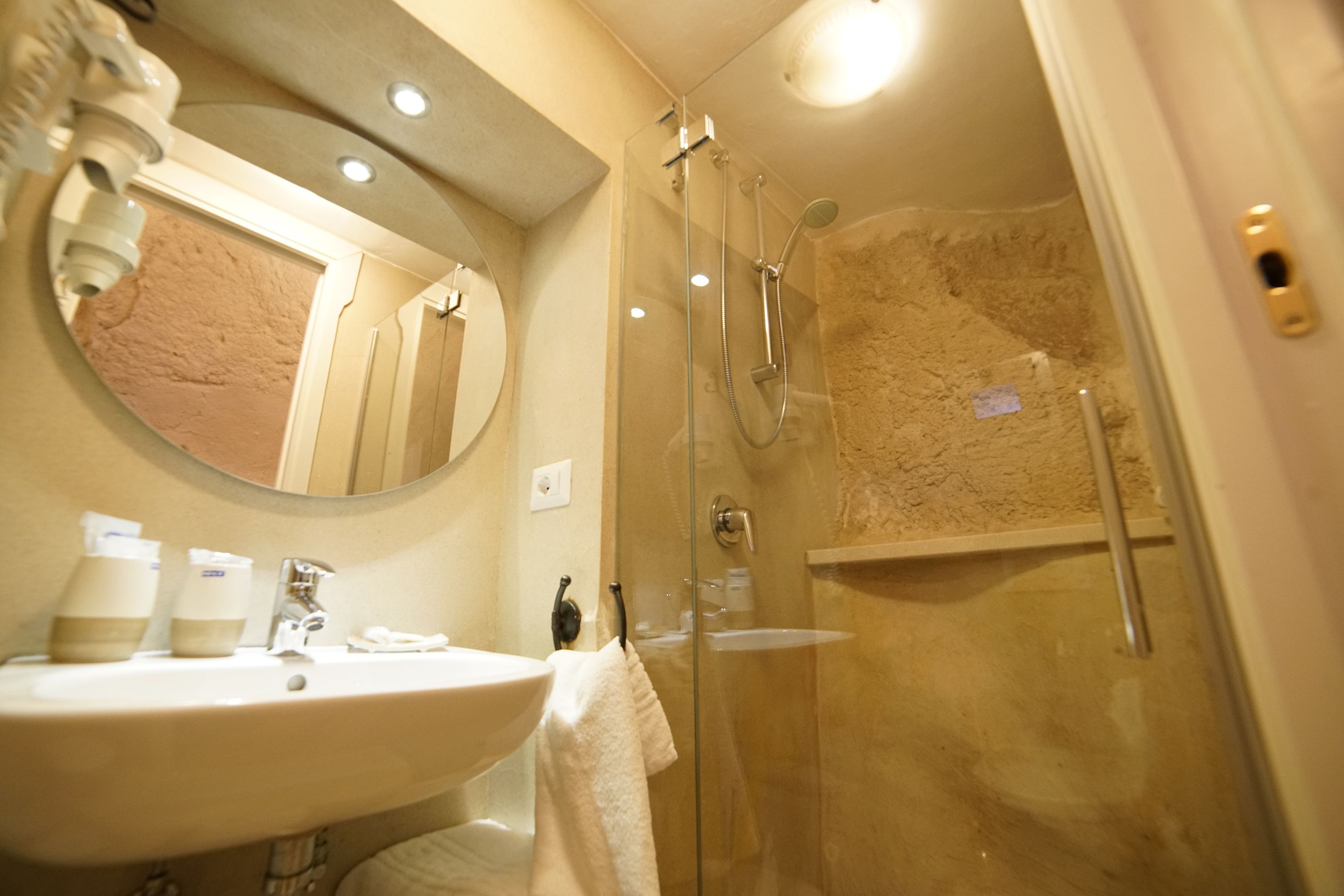 A bathroom with a sink, mirror, and glass-enclosed shower.