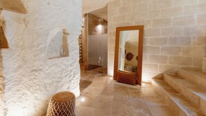A hallway with stone walls, a wooden door, and a tiled floor. - Il Belvedere (Matera)