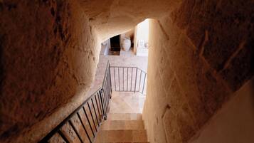Una escalera de piedra que conduce a una habitación con piso de baldosas y barandilla de metal.