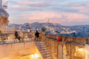 Terraza con asientos al aire libre que da a una vista panorámica de la ciudad al atardecer.