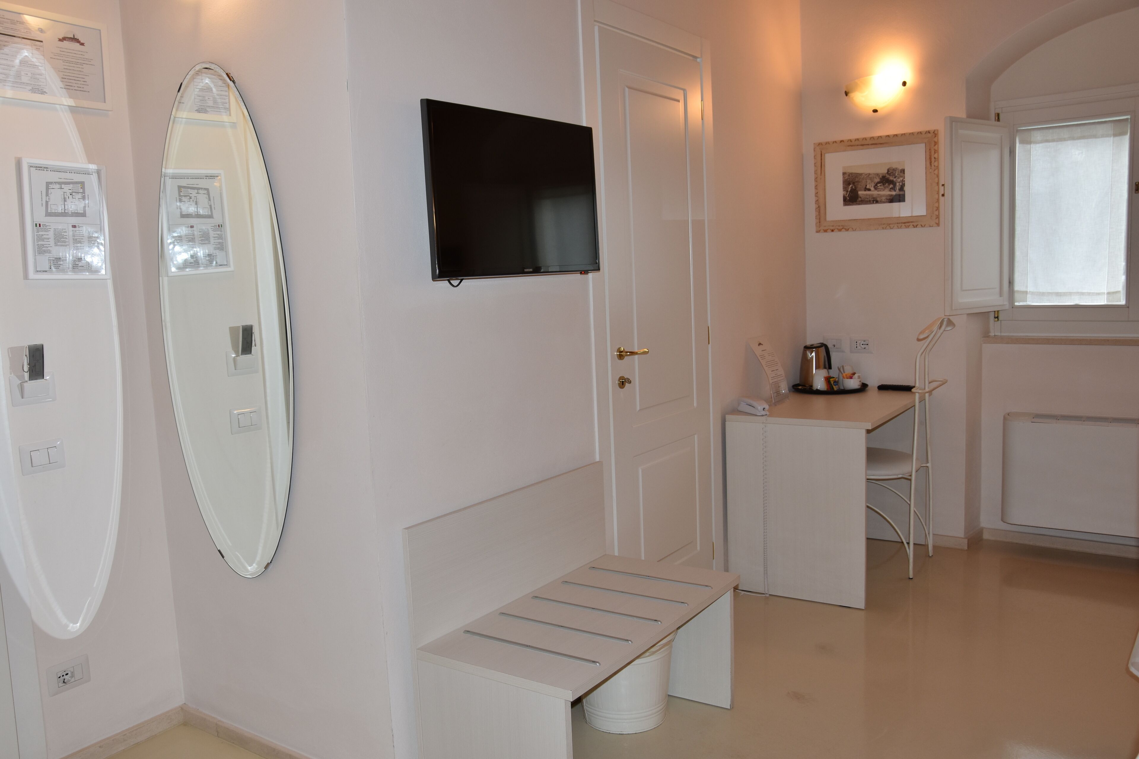 Una camera d'albergo con un letto, una televisione, una scrivania e un bagno.