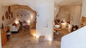 A spacious, well-lit interior with a stone floor, white walls, and a variety of seating options including a sofa, chairs, and a dining table. - Il Belvedere (Matera)