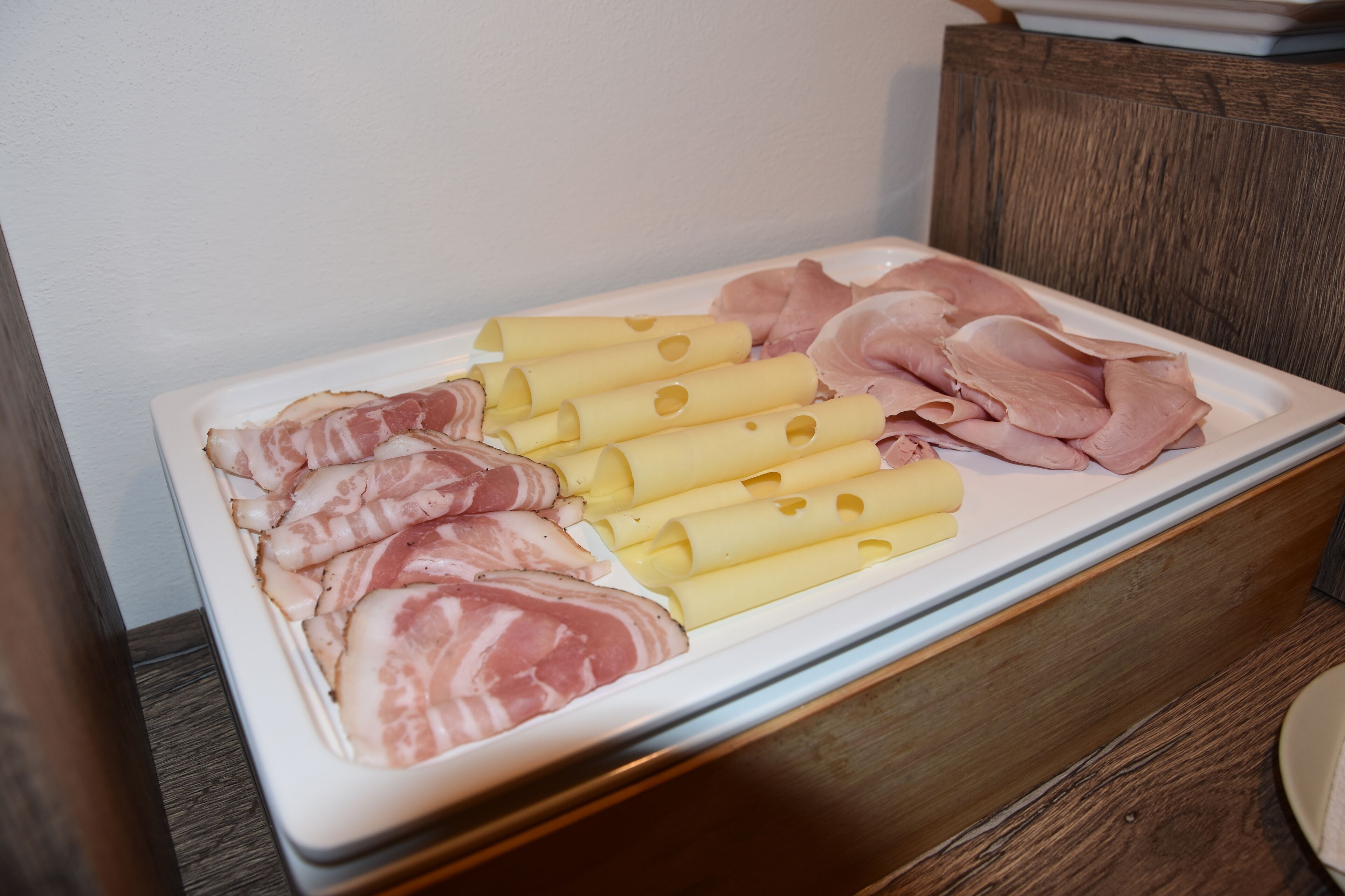A tray of sliced meats and cheeses on a wooden table.