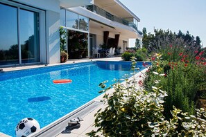 A modern house with a swimming pool, outdoor seating, and a garden with various plants and flowers. - Villa Ayrault (Châtillon-sur-Thouet)