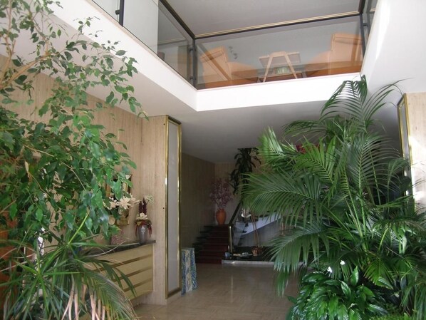 A modern interior with a glass railing, a staircase, and various indoor plants. - Villa Ayrault (Châtillon-sur-Thouet)