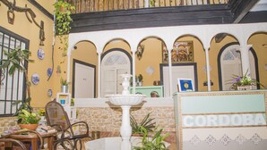 A reception area with a fountain, potted plants, and a reception desk labeled 'CORDOBA'. - Pension Internacional (Córdoba)