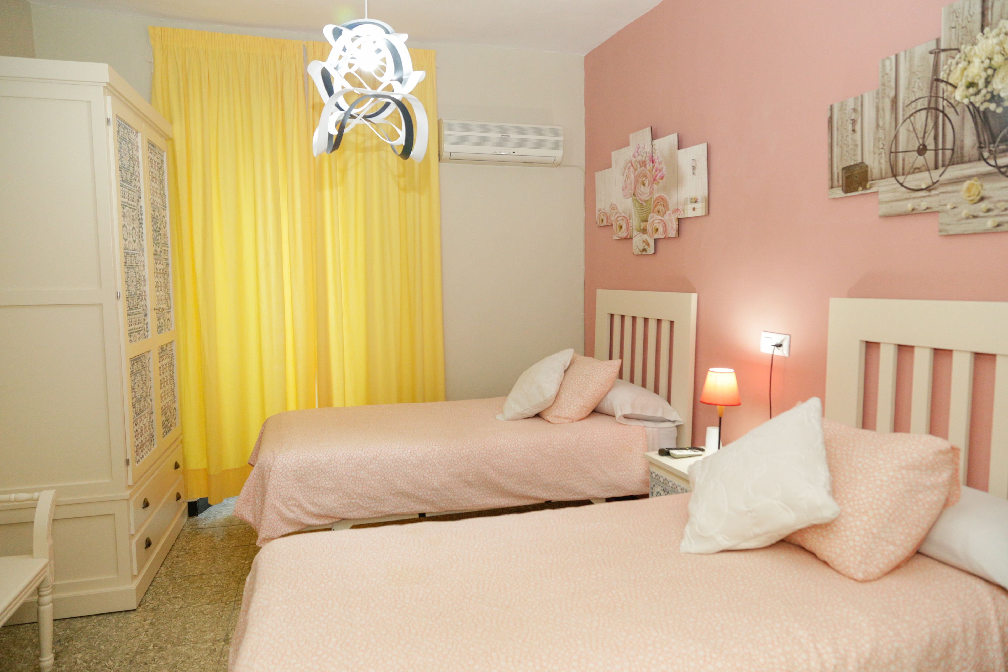 Une chambre avec deux lits, une armoire, une table de chevet et une lampe.