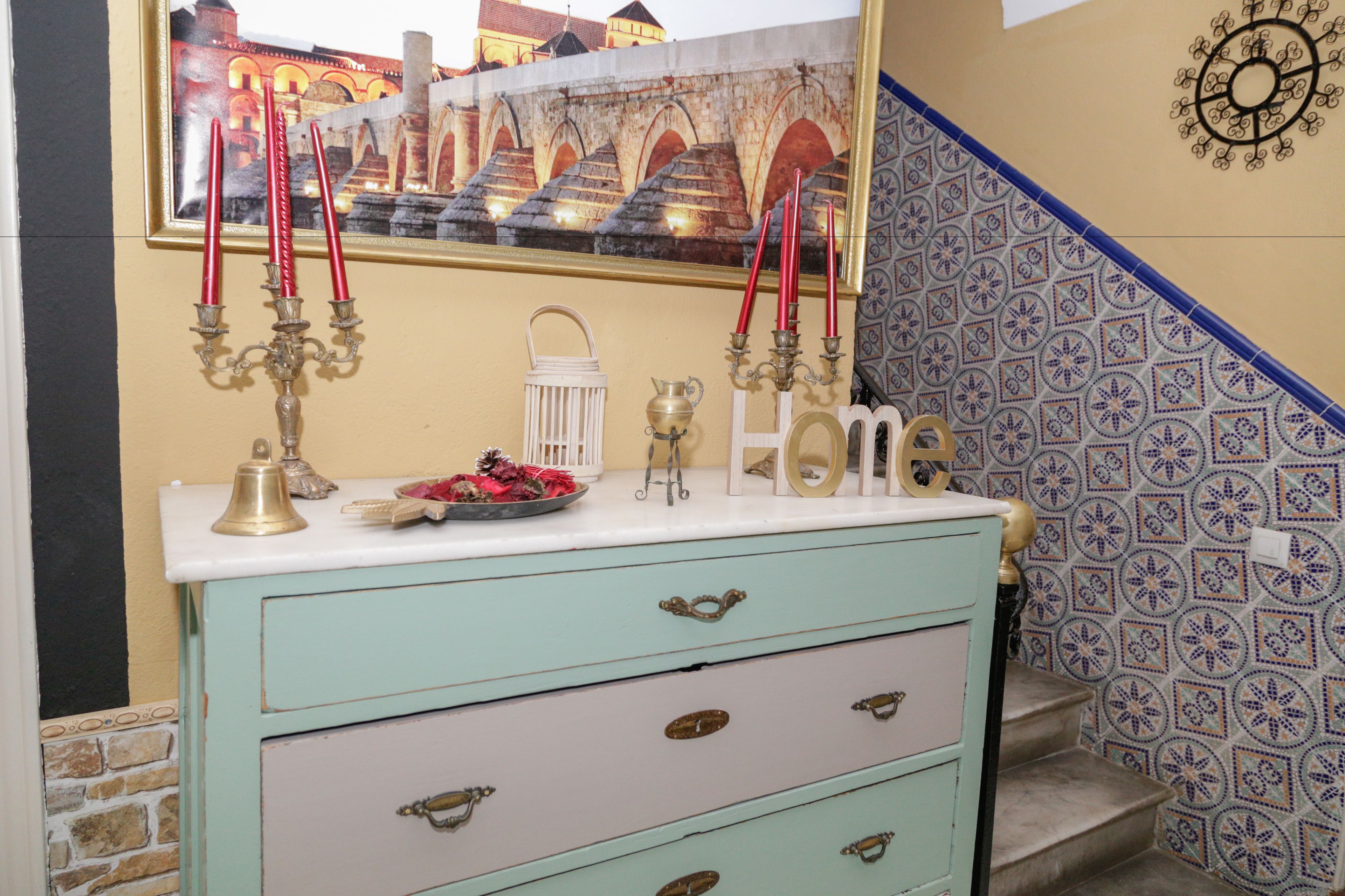 A vintage-style dresser with drawers, a mirror, and a decorative plate with red candles.
