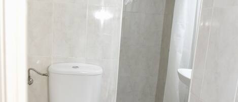 A bathroom with a toilet, a shower, and a sink.