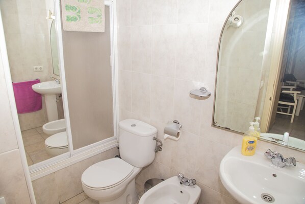 A bathroom with a toilet, bidet, sink, and mirror.