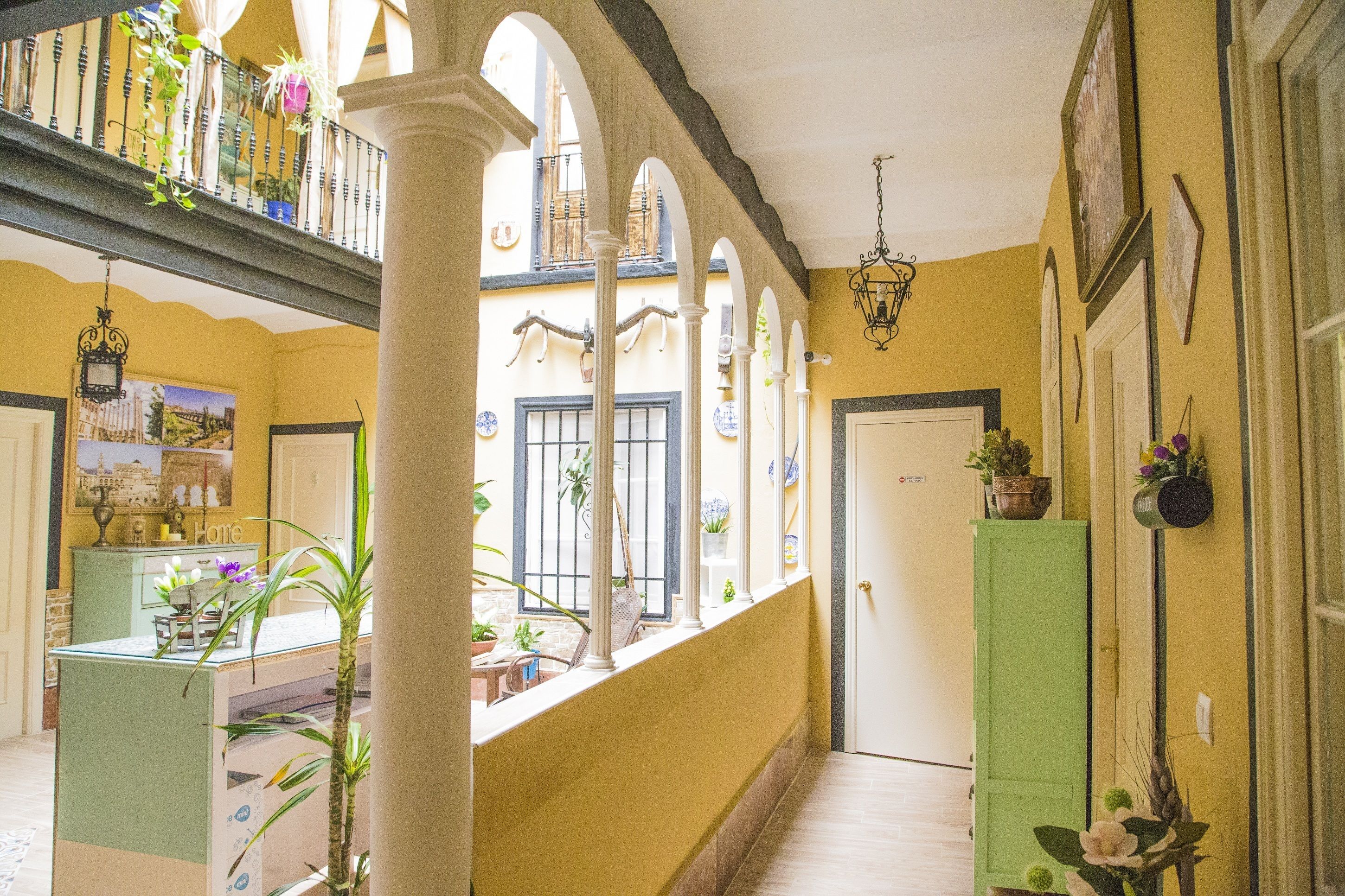 A corridor with arches, a reception desk, and potted plants.