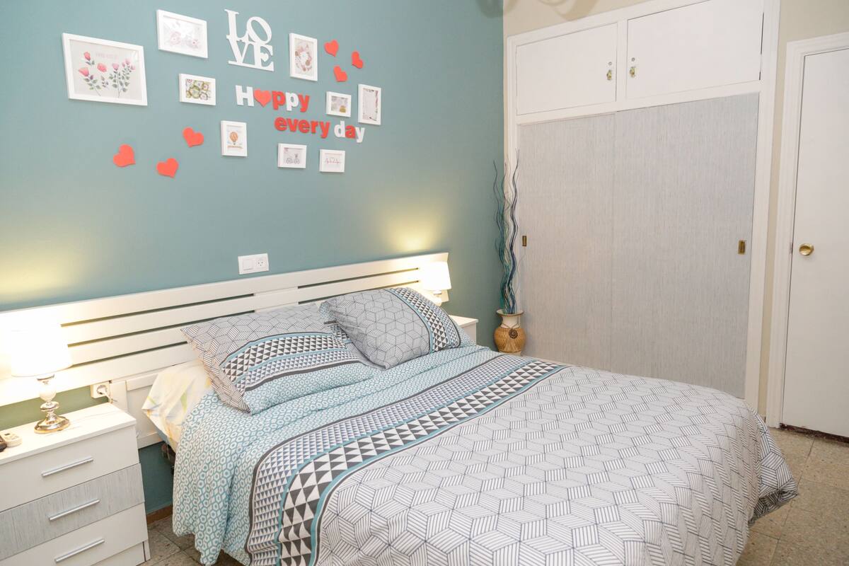 A bedroom with a bed, nightstands, a dresser, and a wardrobe.