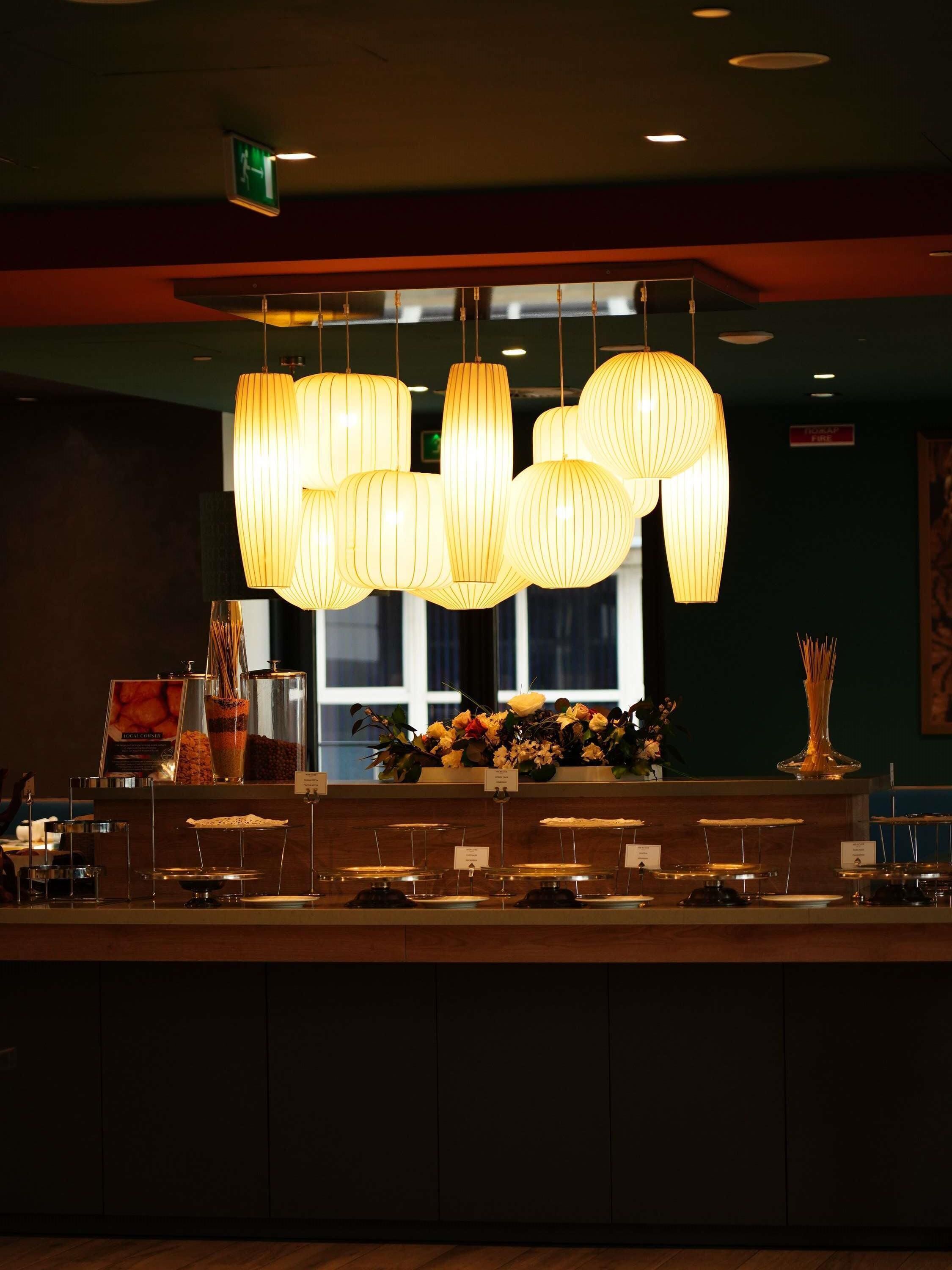 Un espace d’accueil avec un comptoir, des luminaires suspendus et une fenêtre en arrière-plan.