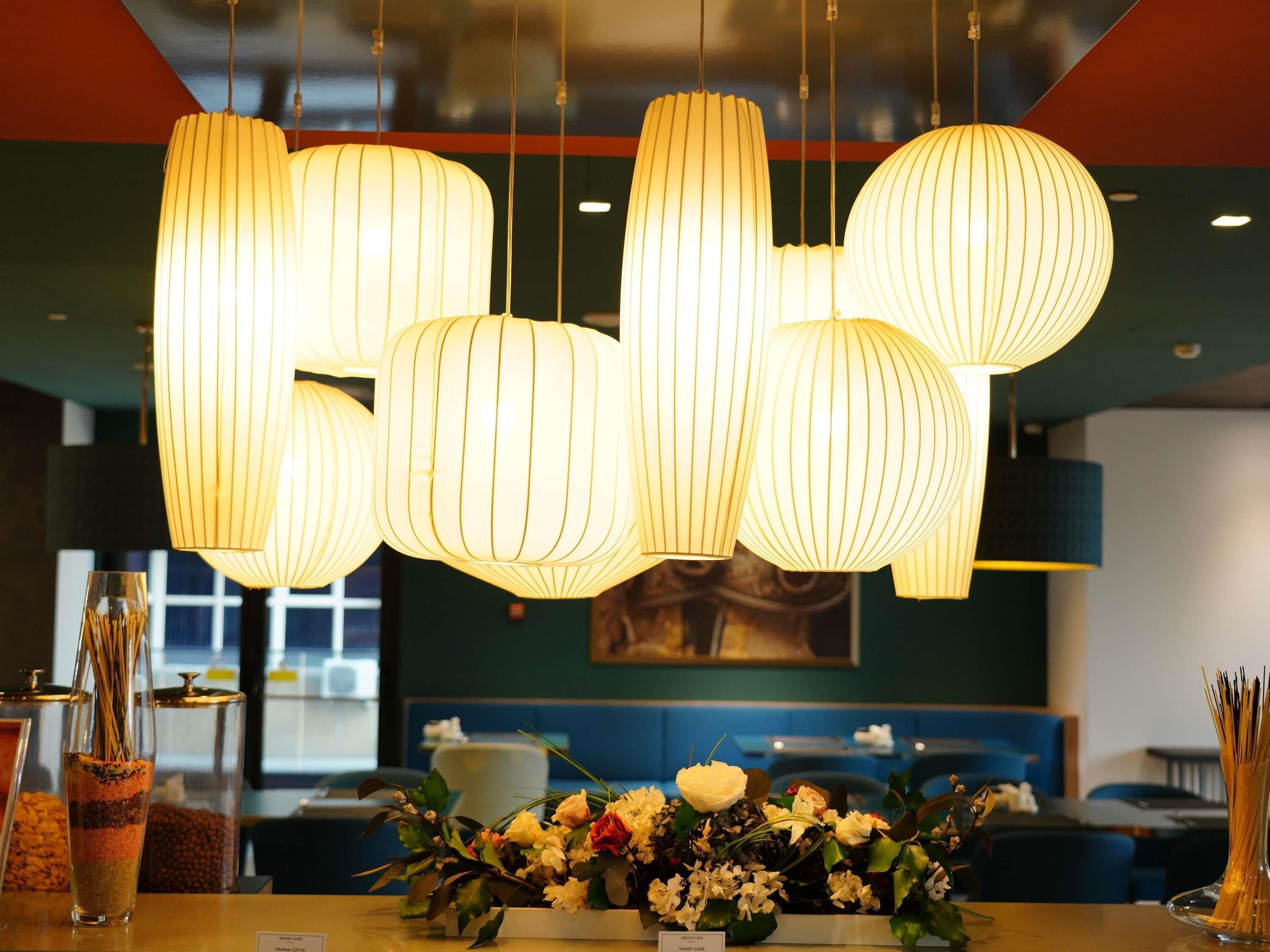 A restaurant interior with hanging paper lanterns, a floral centerpiece, and a view of the dining area.