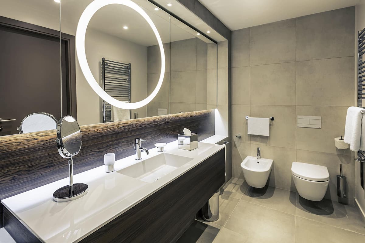 Un baño moderno con un espejo grande, dos lavamanos, un bidé y un inodoro.