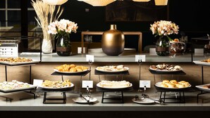 A buffet setup with various food items, a vase with flowers, and hanging light fixtures. - Mercure Almaty City Center (Almaty)
