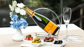 Una botella de champán, una copa, una mesa con fruta y flores.
