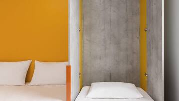 Une pièce avec un lit, un mur jaune et un mur en béton gris.