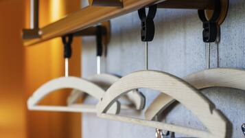 A close-up of a wooden rack with multiple hangers, attached to a metal rod, against a textured wall.