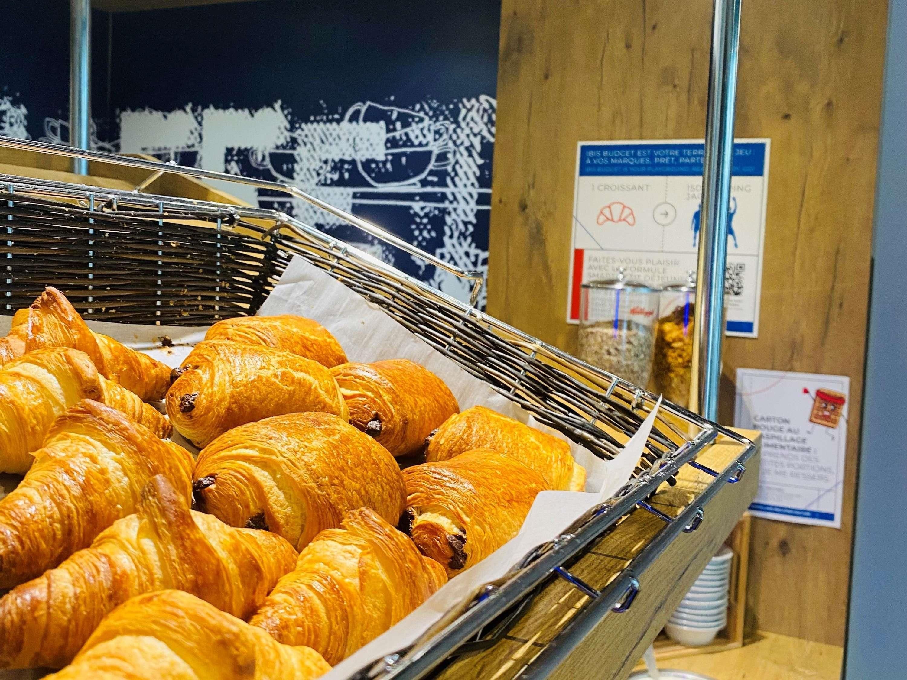 En anvisning af gyldenbrune croissanter i en metal kurv, med informationsskilte i baggrunden.