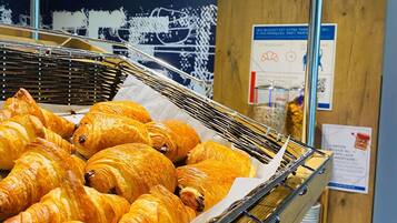 En anvisning af gyldenbrune croissanter i en metal kurv, med informationsskilte i baggrunden.