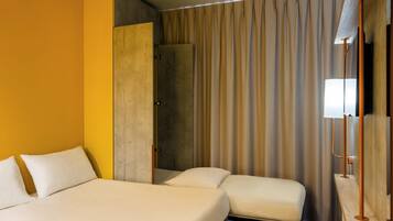 Een hotelkamer met een bed, een zithoekje, een douche en een gordijn.